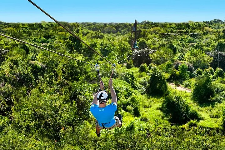 A zipline rider over green forest
